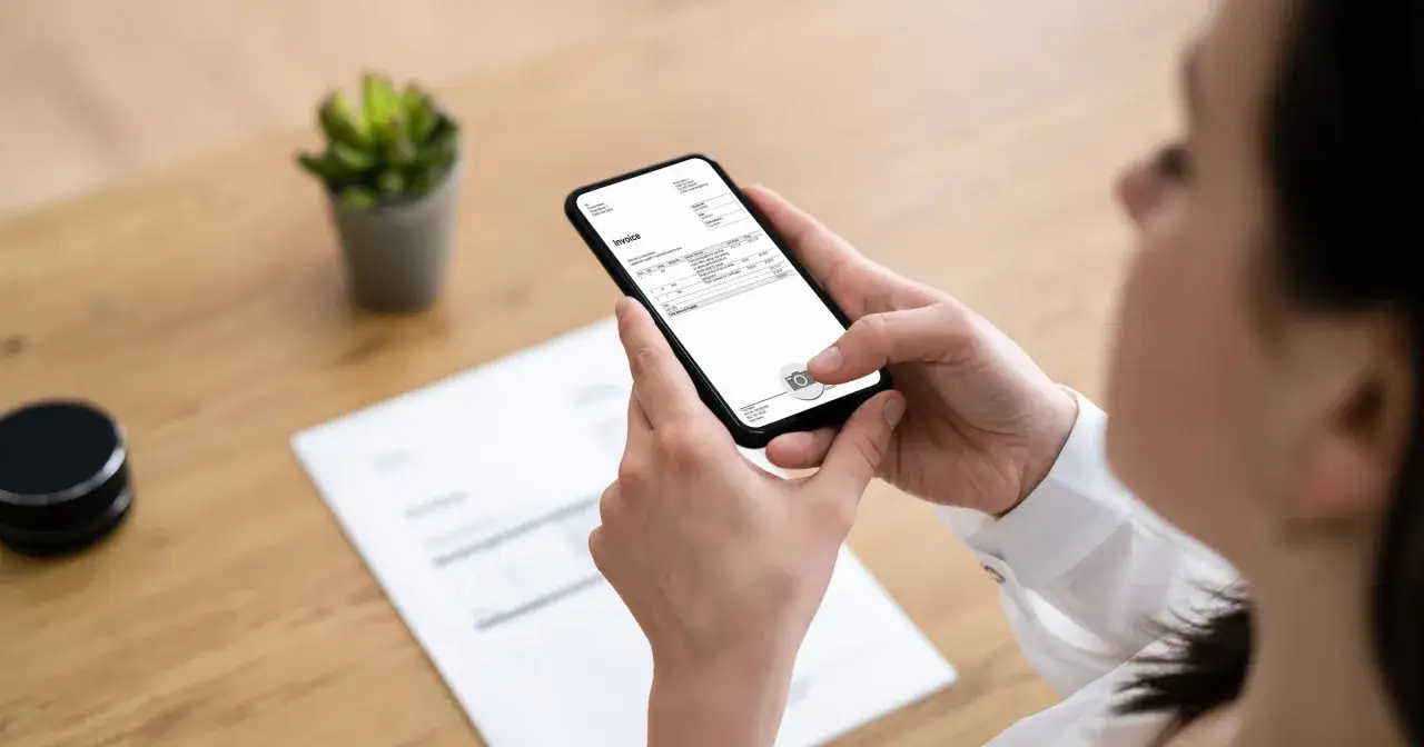 Kobieta używa aplikacji, która przepisuje tekst ze zdjęcia faktury na ekranie telefonu.