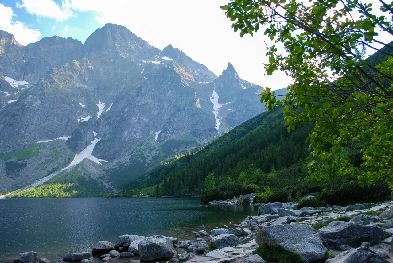 Jezioro Morskie Oko otoczone skalistymi szczytami Tatr i gęstym lasem. Wspaniałe tatry atrakcje dla każdego miłośnika przyrody.