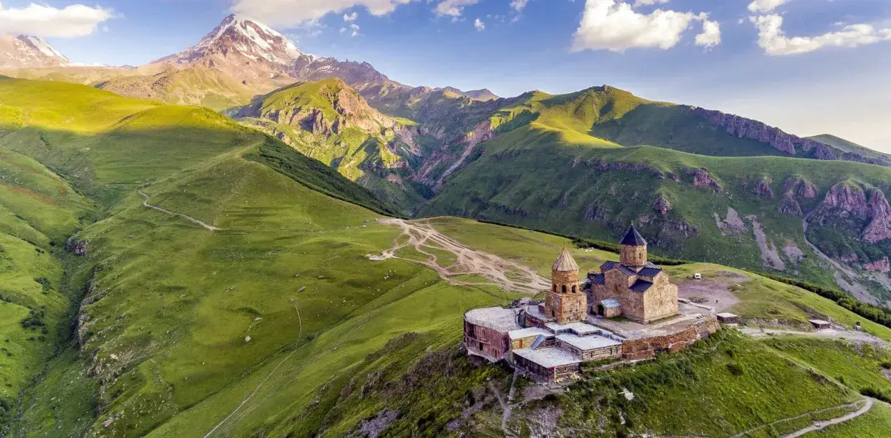 Kości&oacute;ł Gergeti na tle g&oacute;r Kaukazu. Idealne miejsce na trekking w Gruzji.