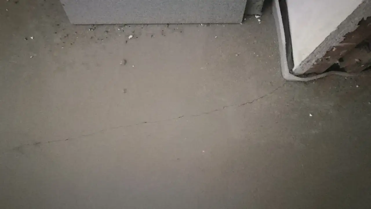 Szara, świeża wylewka z widocznym pęknięciem. W tle fragmenty ścian i gruz. Czas na dalsze prace budowlane po wylewkach.