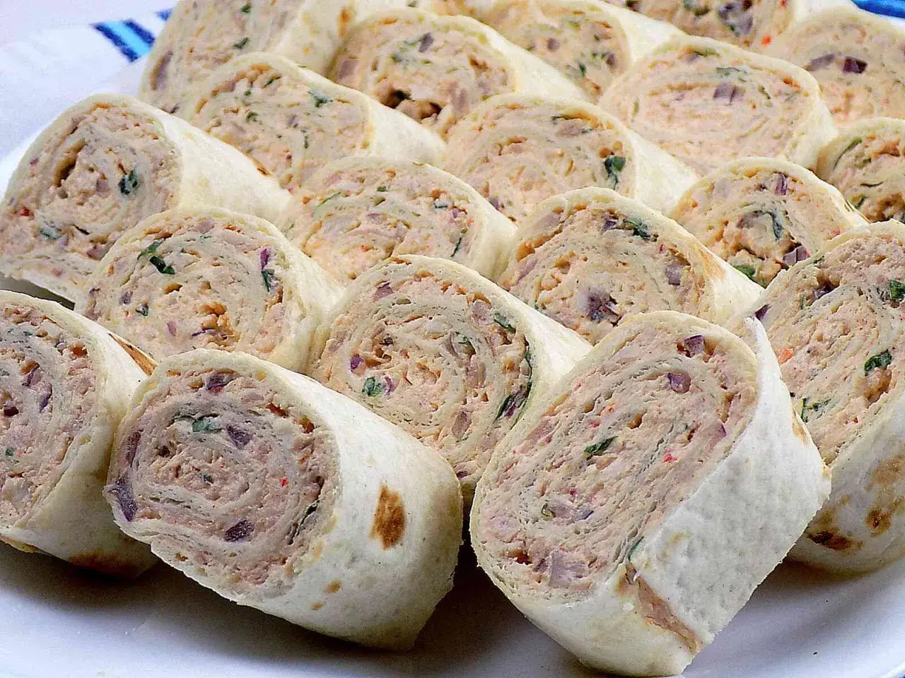 Roladki z tortilli z kremowym farszem i ziołami, idealne jako przekąski.