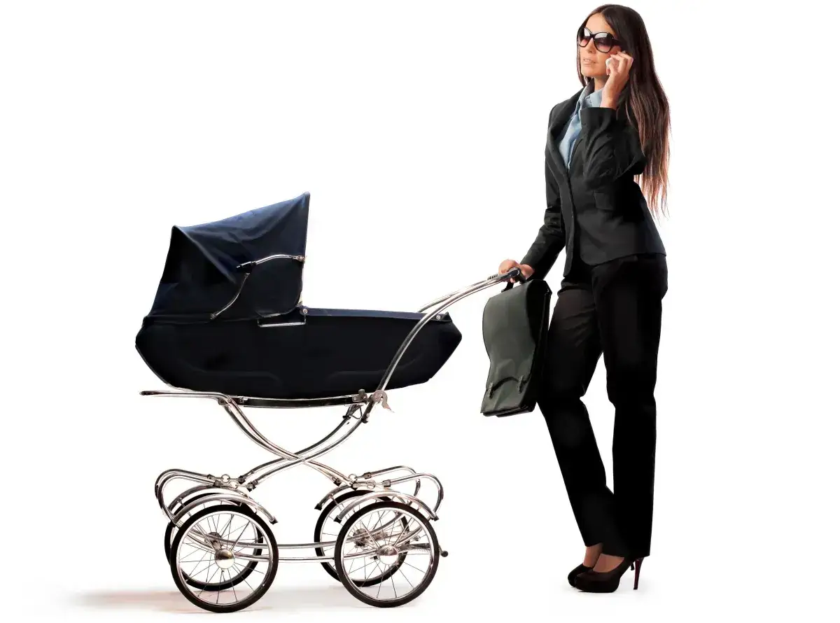 Kobieta w garniturze pcha wózek, rozmawiając przez telefon. Czy macierzyński wlicza się do emerytury?