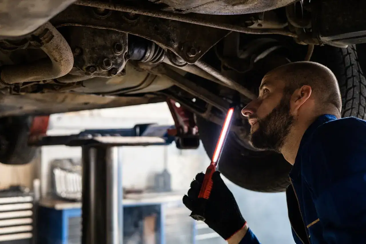 Mechanik bada podwozie auta, szukając przyczyny chrobotania przy skręcaniu kierownicą.