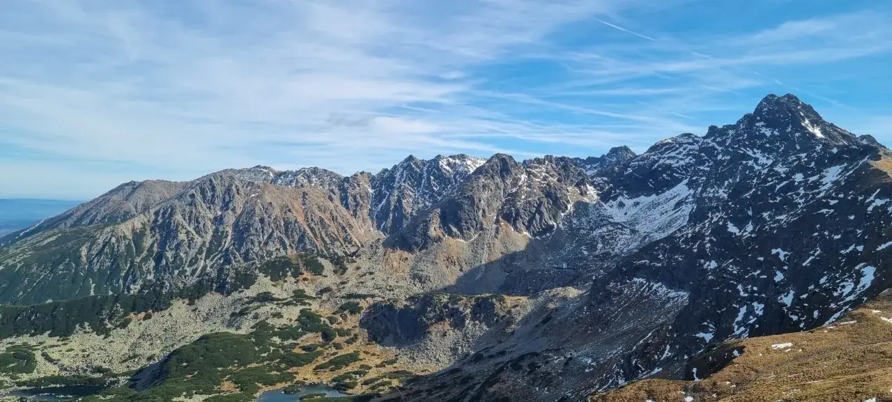 Majestatyczne Tatry z ośnieżonymi szczytami. Widok na skaliste zbocza i doliny, gdzie widać, ile ma Kasprowy Wierch.