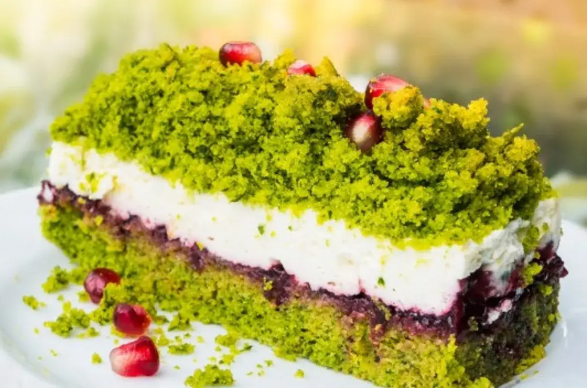 Zielone ciasto leśny mech z mascarpone, przełożone kremem i owocami, ozdobione pestkami granatu.