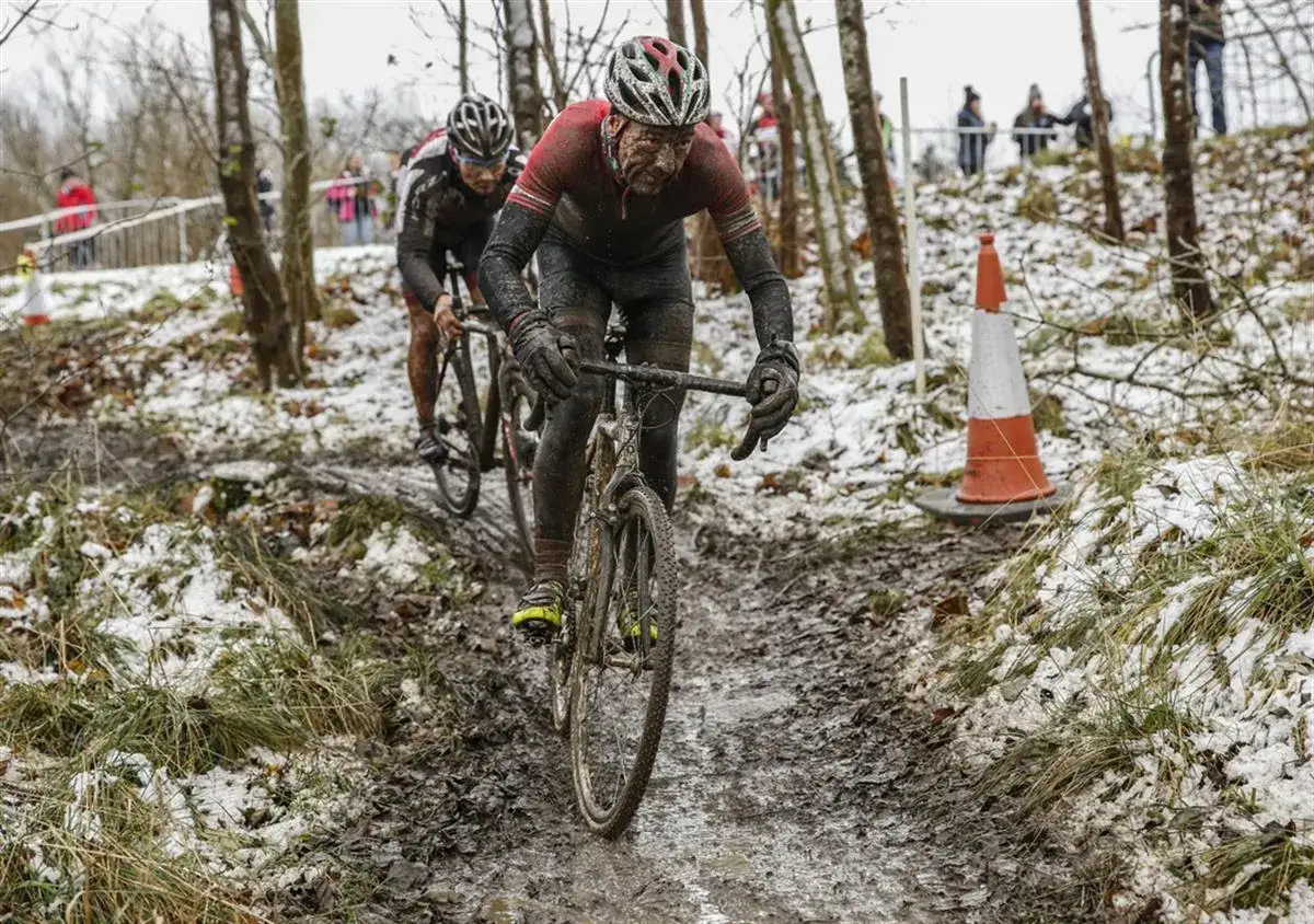 Dw&oacute;ch kolarzy w błocie i śniegu walczy na trasie. To trudny wyścig przełajowy, a nie spokojna jazda gravel.