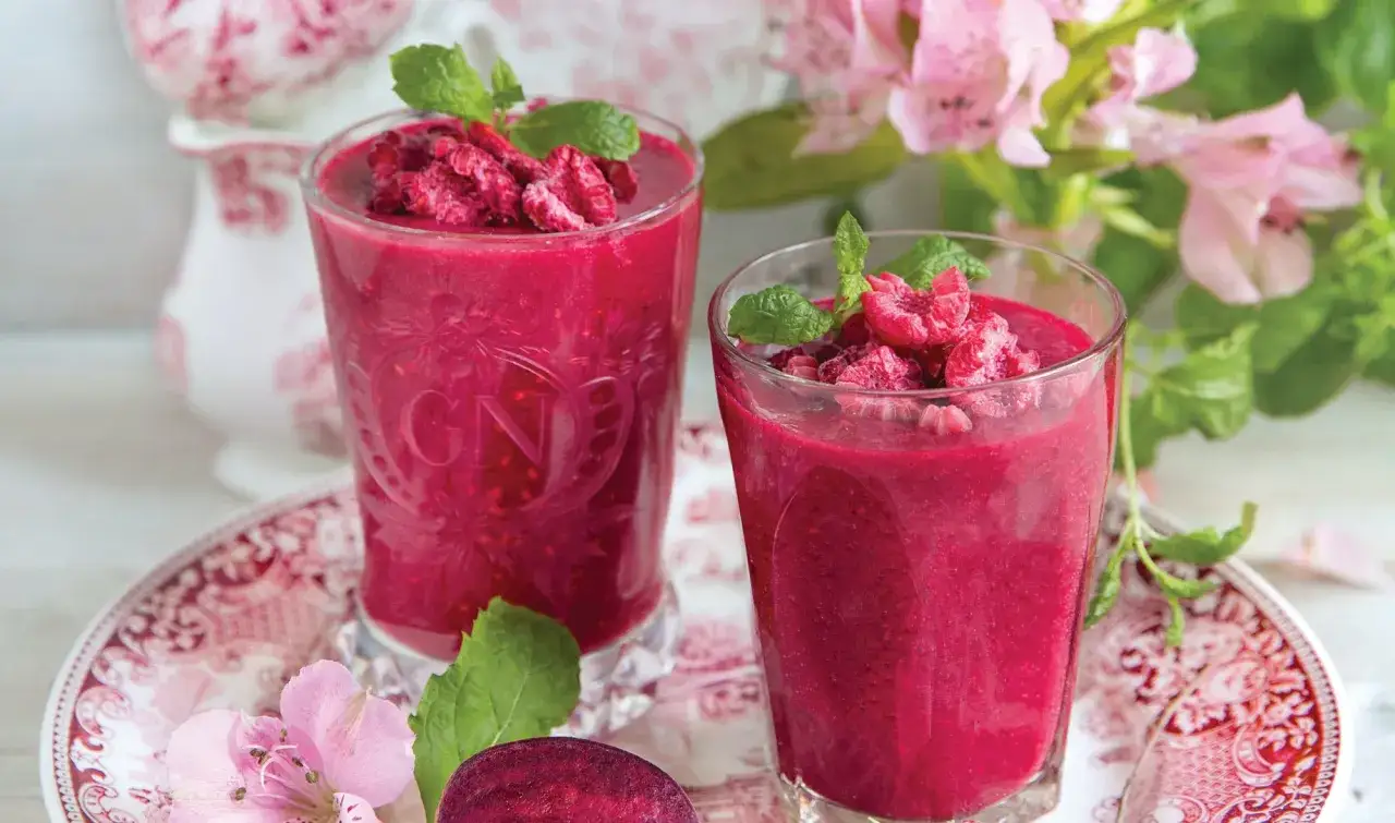 Dwa szklanki pysznych, malinowych koktajli, które mogą być inspiracją do stworzenia własnych przepisów na zdrowe koktajle. Udekorowane malinami i miętą.