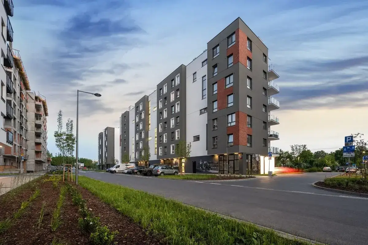 Nowoczesne bloki mieszkalne, obok budowa. Zastanawiasz się, ile kosztuje kupno mieszkania w takiej lokalizacji?