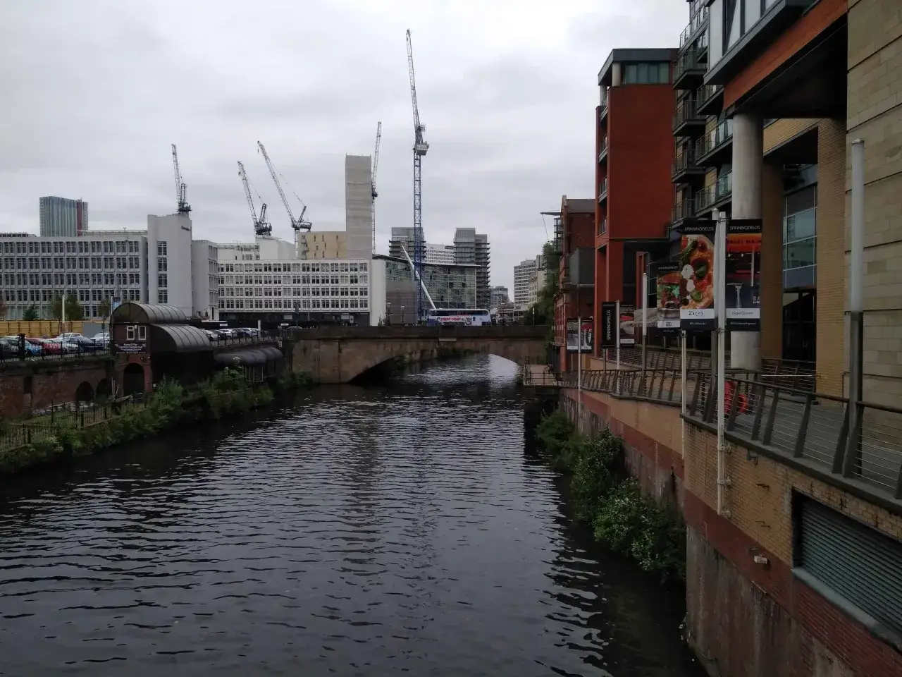 Widok na kanał w Manchesterze, z nowoczesnymi budynkami i dźwigami w tle. Idealne miejsce, by zobaczyć, jak rozwija się miasto.