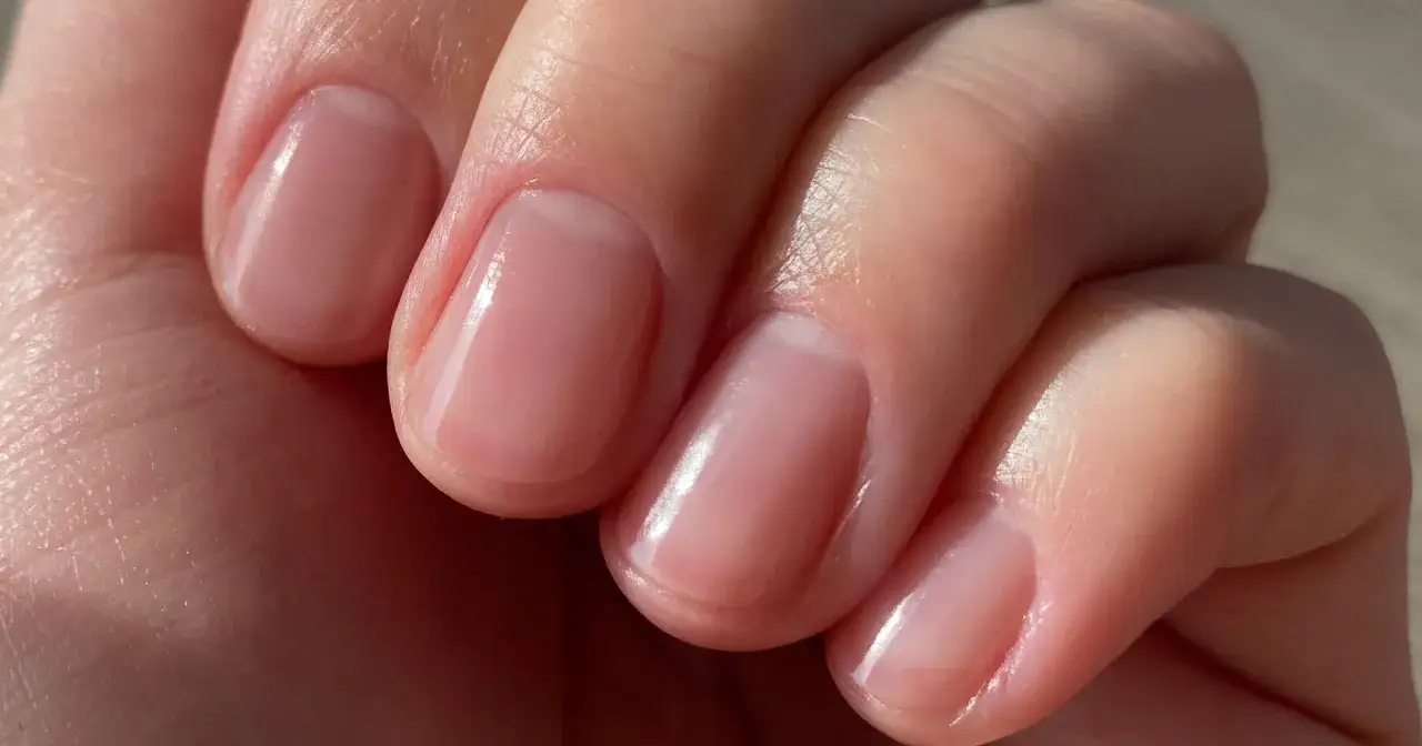 Delikatne, różowe paznokcie po zabiegu. Choć naturalne, mogą pojawić się drobne wady, jak nierówności, które manicure japoński stara się ukryć.