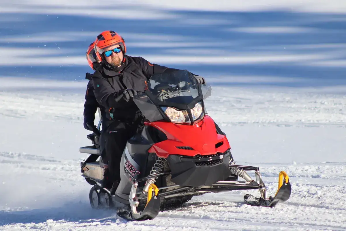 Dw&oacute;ch mężczyzn na skuterach śnieżnych w Bukowinie, cieszących się zimową przygodą na śniegu.