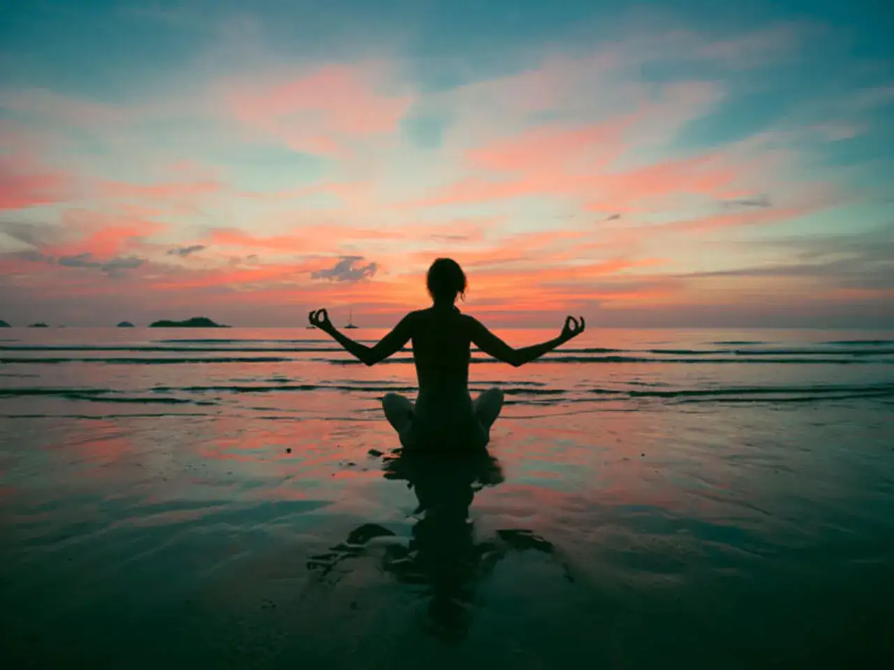Sylwetka osoby w pozycji medytacyjnej na plaży o zachodzie słońca. Idealna medytacja na dobry dzień.