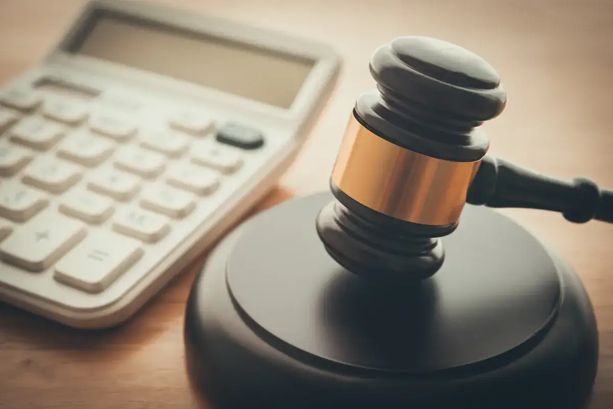 Młotek sędziowski i kalkulator. Zastanawiasz się, ile kosztuje porada u notariusza?
