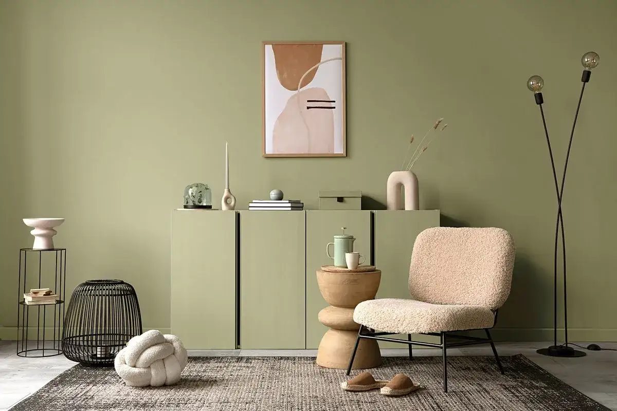 Przytulny salon w odcieniu kolor szałwiowy. Miękkie tekstylia i abstrakcyjne obrazy tworzą relaksującą atmosferę.