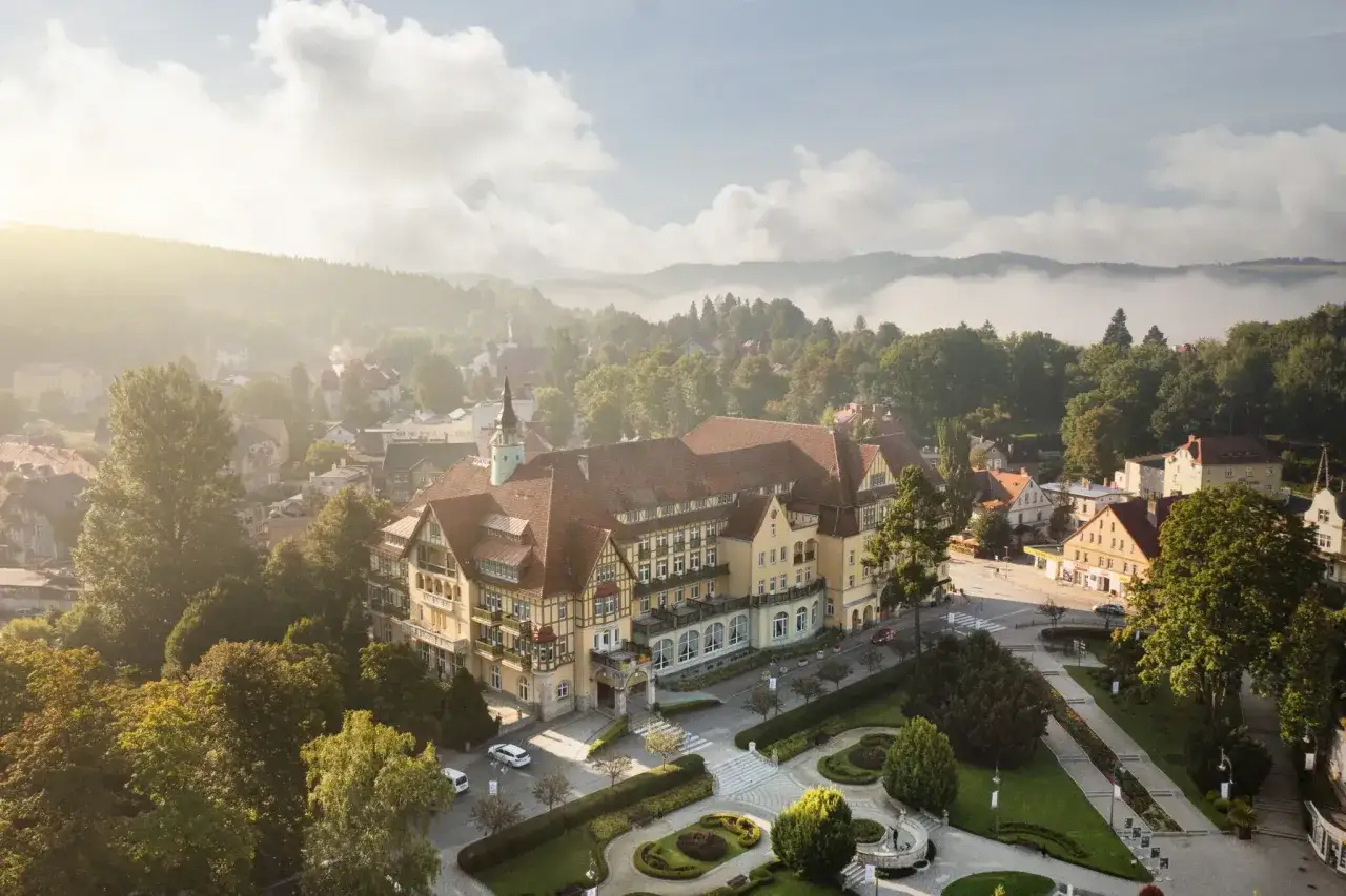 Sanatorium Polonia w Kudowie Zdroju, z pięknymi pokojami i otoczeniem, w mglisty poranek.
