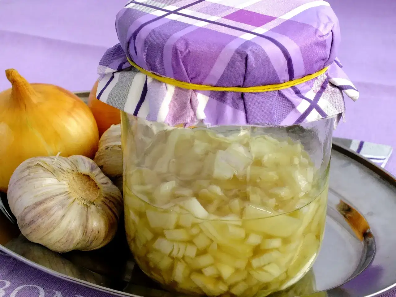 Słoik z domowym syropem z cebuli, obok świeże cebule i czosnek. Naturalny lek na przeziębienie.