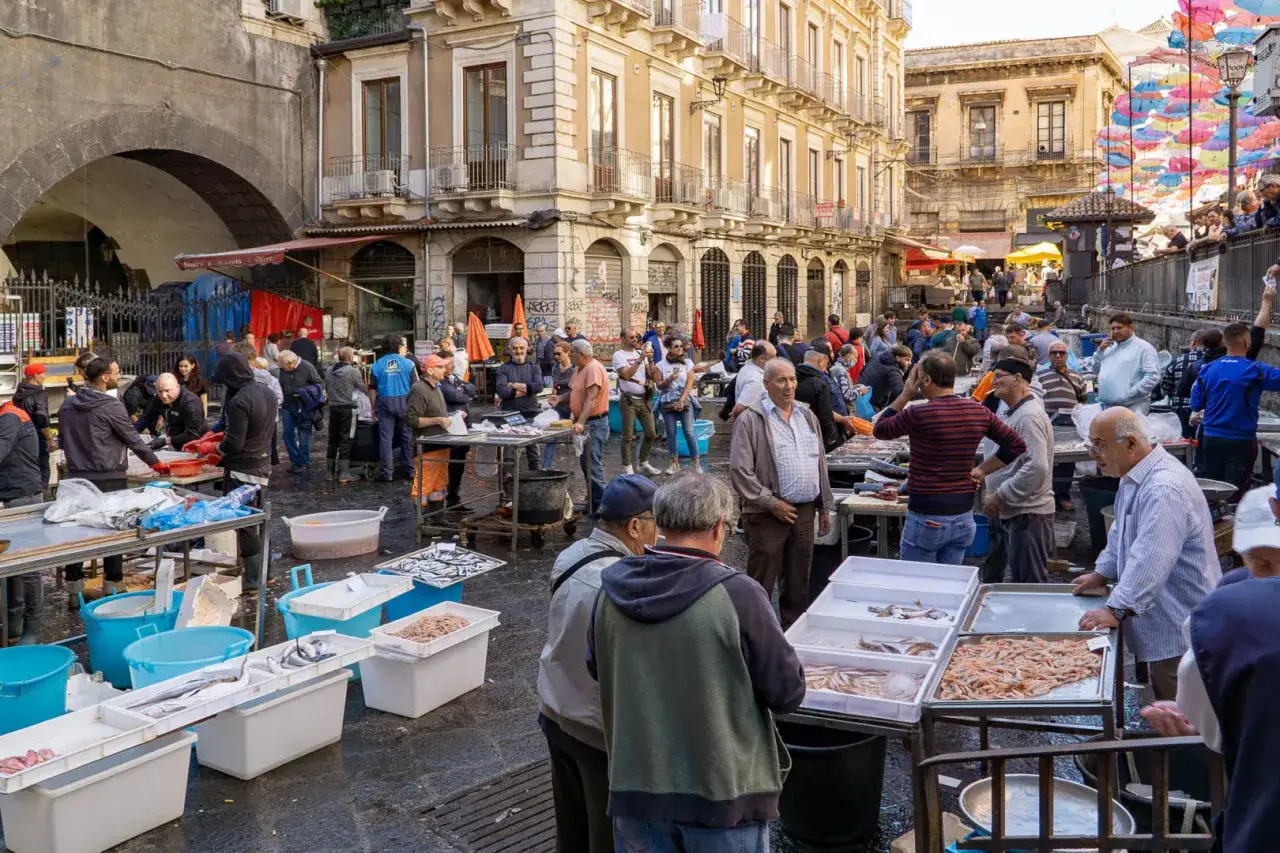Targ rybny w Katanii. Czy warto? Tłum ludzi, świeże ryby i owoce morza na straganach.