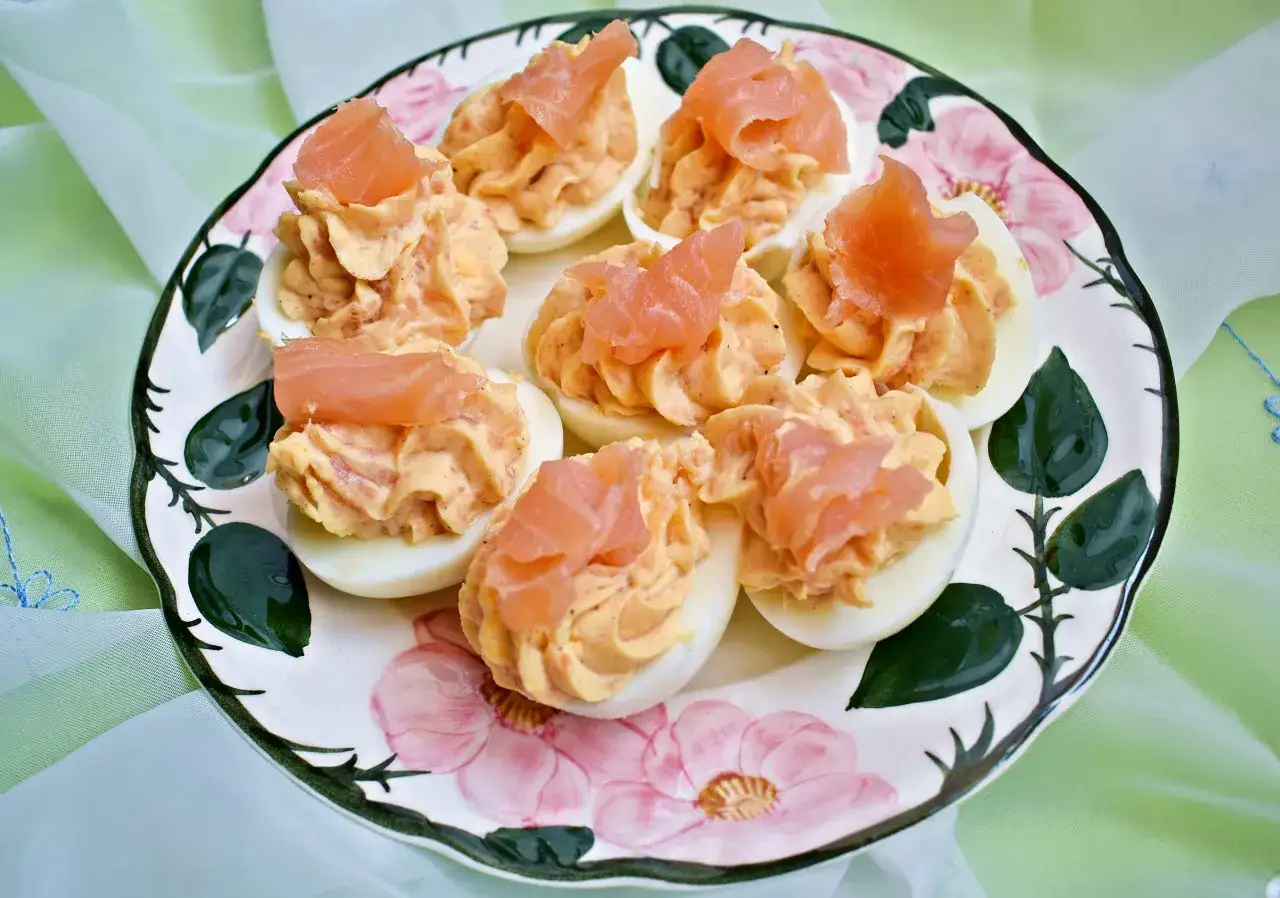Pyszne jajka faszerowane z łososiem, udekorowane na ozdobnym talerzu. Idealna przekąska na każdą okazję.