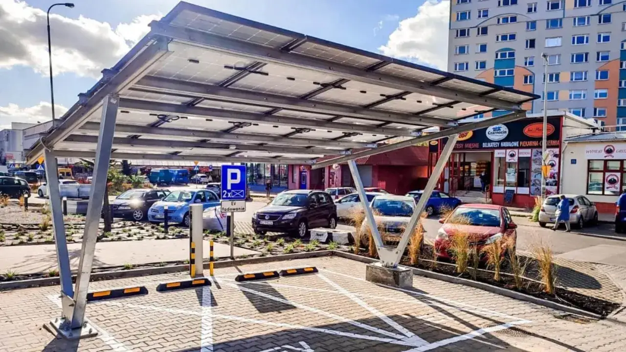 Nowoczesne wiaty garażowe z panelami słonecznymi na parkingu. Samochody elektryczne mogą się ładować pod zadaszeniem.