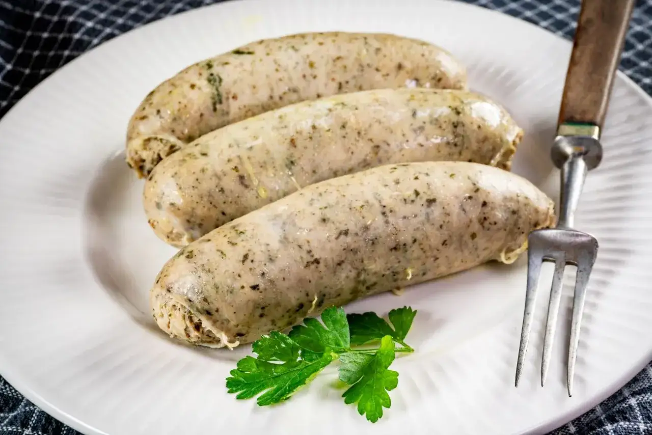 Trzy białe kiełbasy na talerzu, gotowe do podania. Dowiedz się, jak ugotować białą kiełbasę, by była idealna.