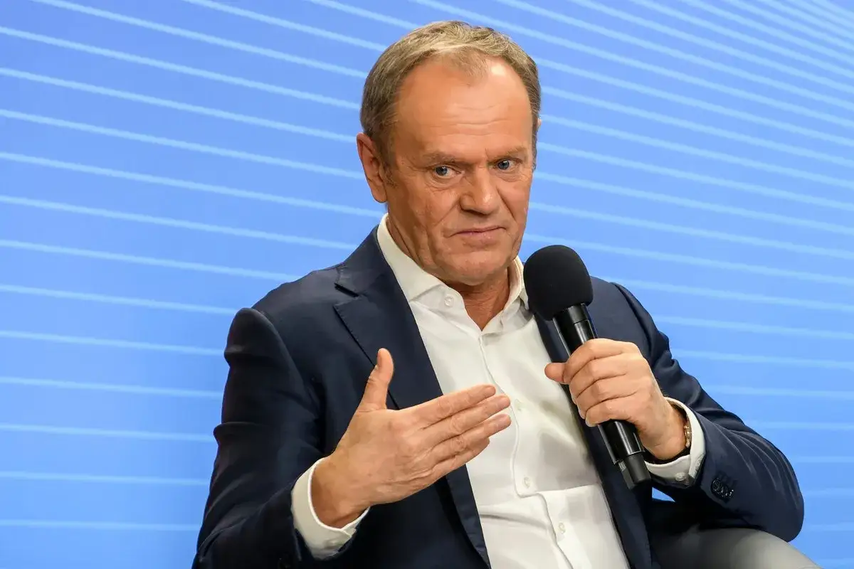 Donald Tusk w garniturze, z mikrofonem w dłoni, dyskutuje o tym, ile Tusk ma emerytury na rękę.