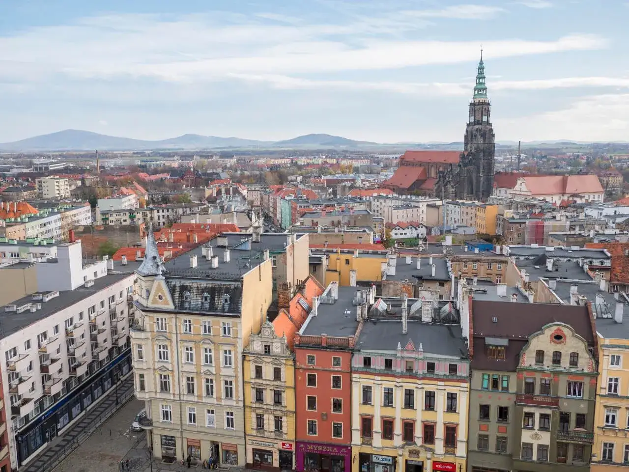 Widok na Świdnicę z górującą nad miastem katedrą. Kolorowe kamienice i dachy tworzą malowniczy krajobraz, ukazując urokliwe świdnickie atrakcje.
