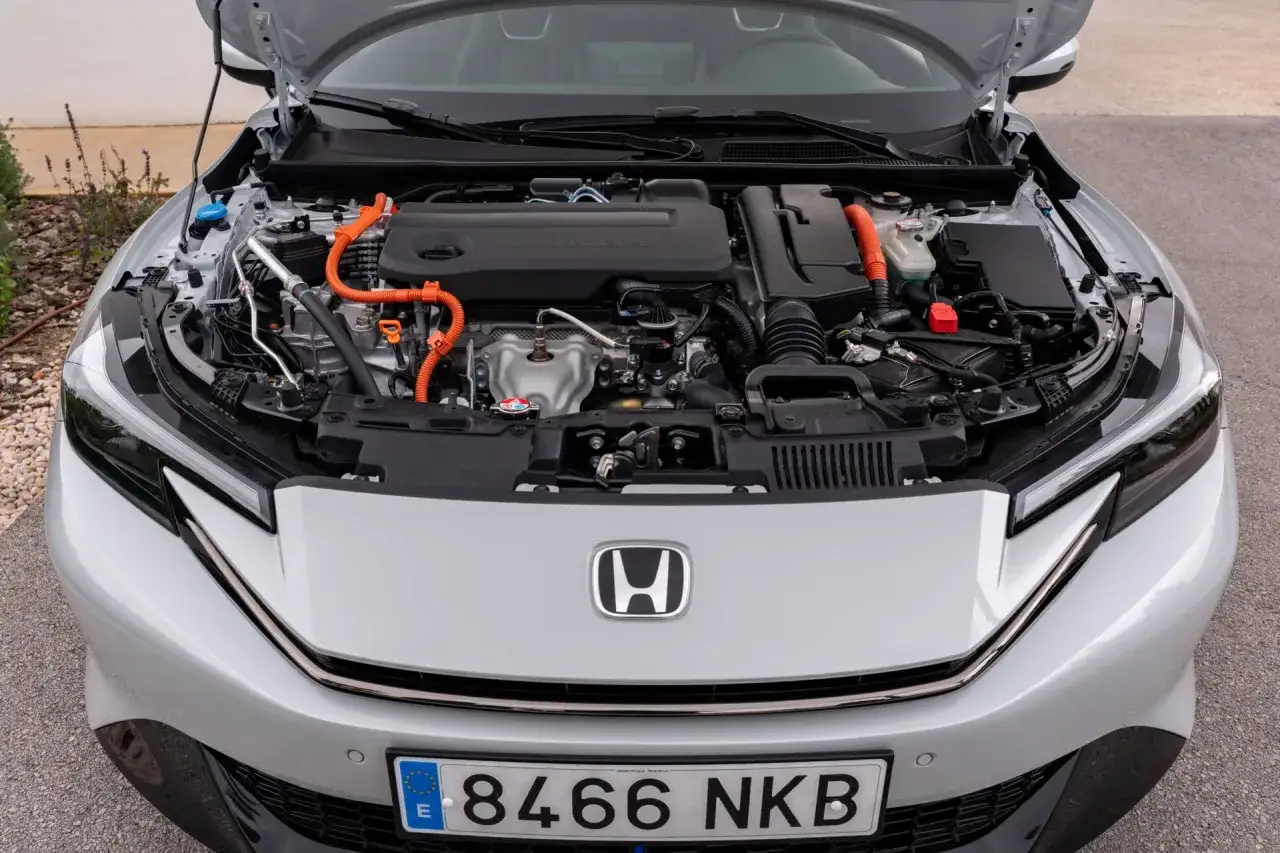 Silnik hybrydowy Hondy, być może w nowej odsłonie modelu Prelude, z widocznymi pomarańczowymi przewodami i logo Honda.