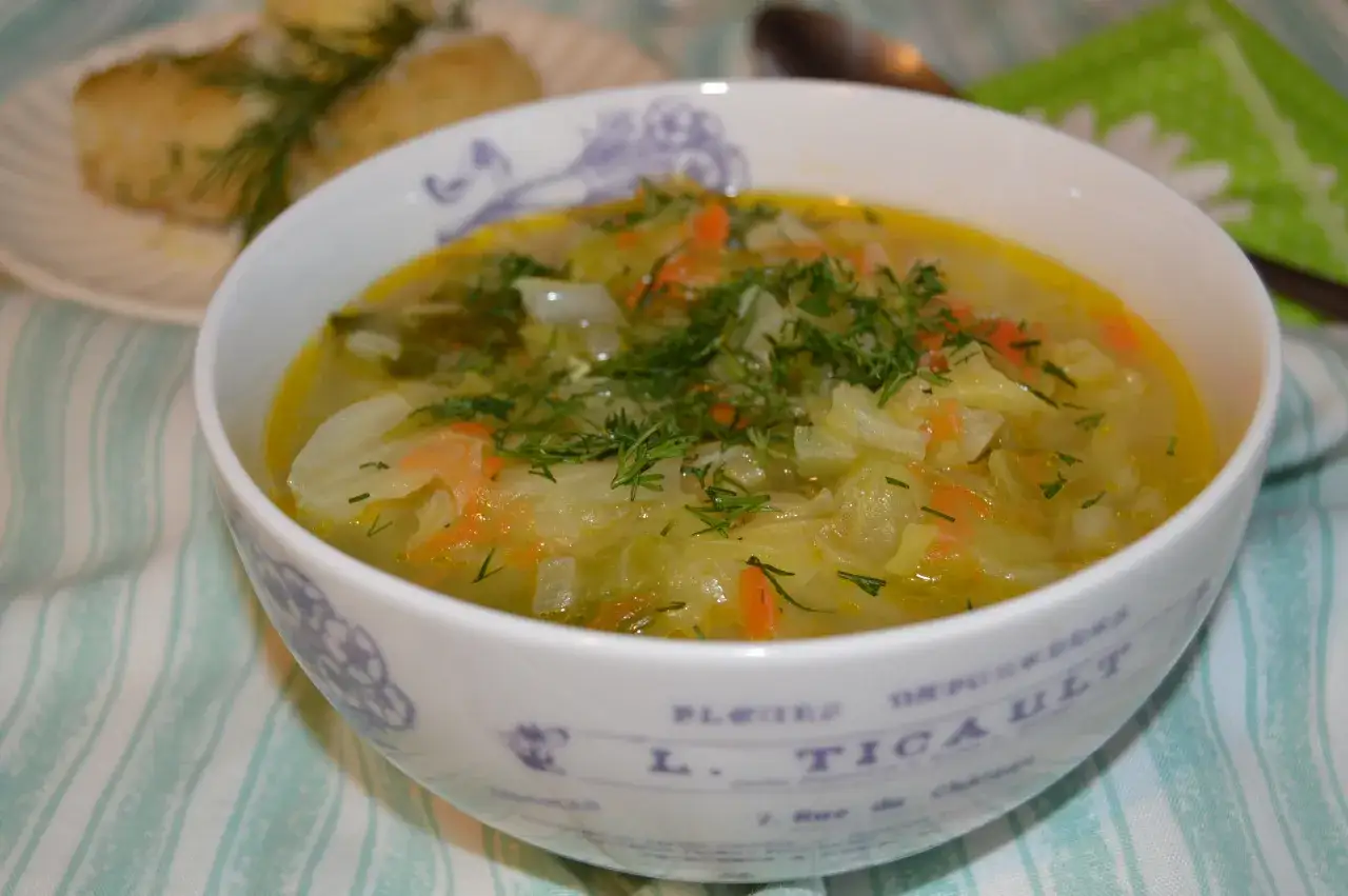 Aromaticzny kapuśniak z młodej kapusty, z marchewką i koperkiem, podany w ozdobnej misce.