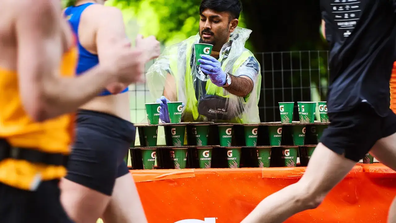 Wolontariusz podaje napój biegaczom. Kluczowe dla przygotowania do maratonu jest nawadnianie.