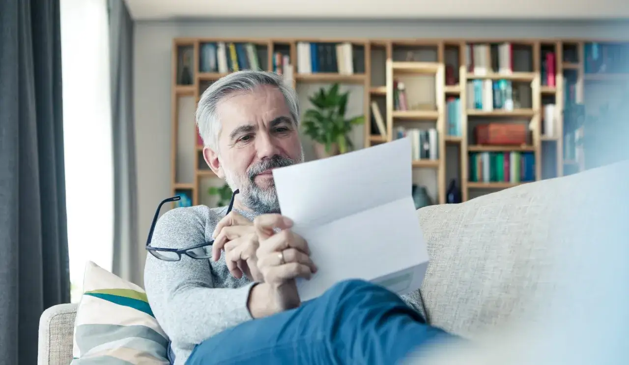 Mężczyzna czyta dokumenty, szukając informacji o ubezpieczeniowym funduszu gwarancyjnym jak uniknąć kary.