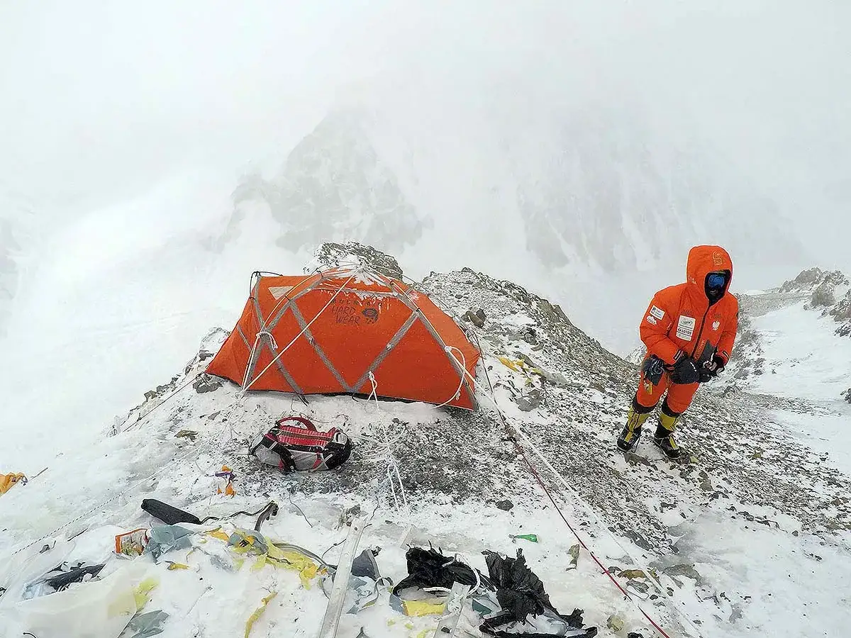 Pomarańczowy namiot i wspinacz w kombinezonie na śnieżnym zboczu. Czy warto brać udział w komercyjnych wyprawach na ośmiotysięczniki?