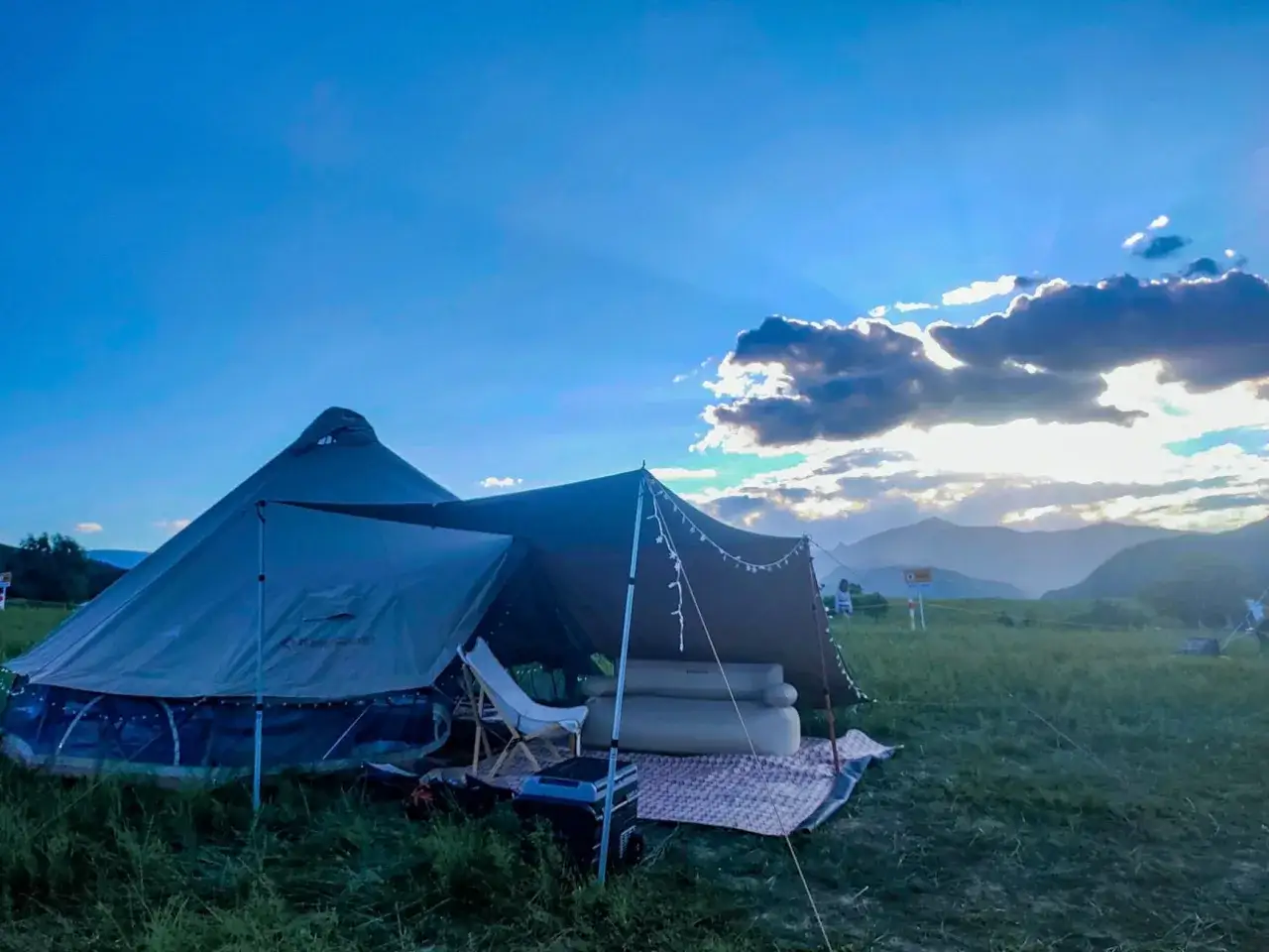 Namiot typu tipi i rozkładany namiot tworzą przytulne schronienie. R&oacute;żne rodzaje namiot&oacute;w na kempingu pod błękitnym niebem.