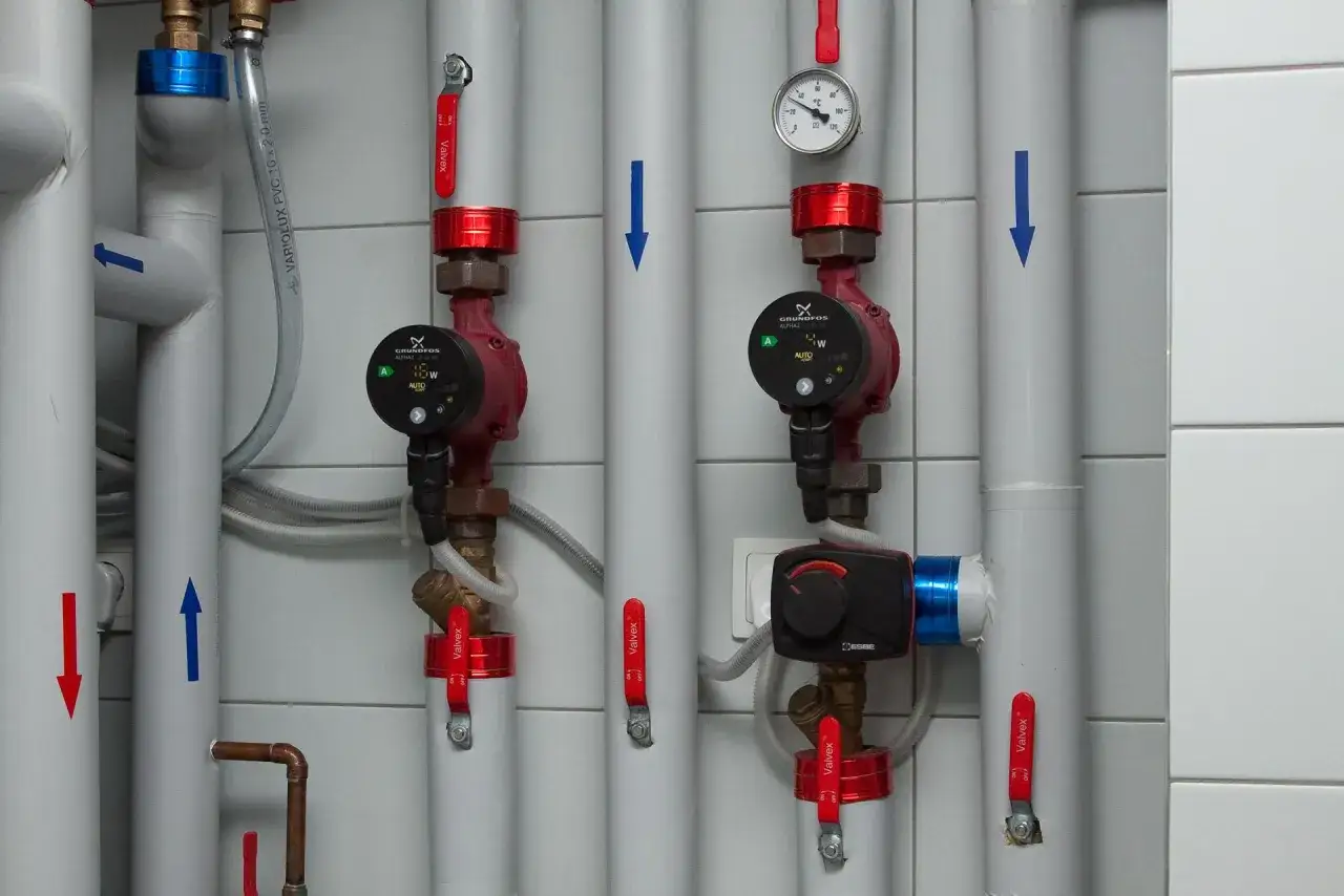 Instrukcja jak ustawić zaw&oacute;r 3-drożny. Widoczne pompy obiegowe, manometr i zawory na instalacji grzewczej.