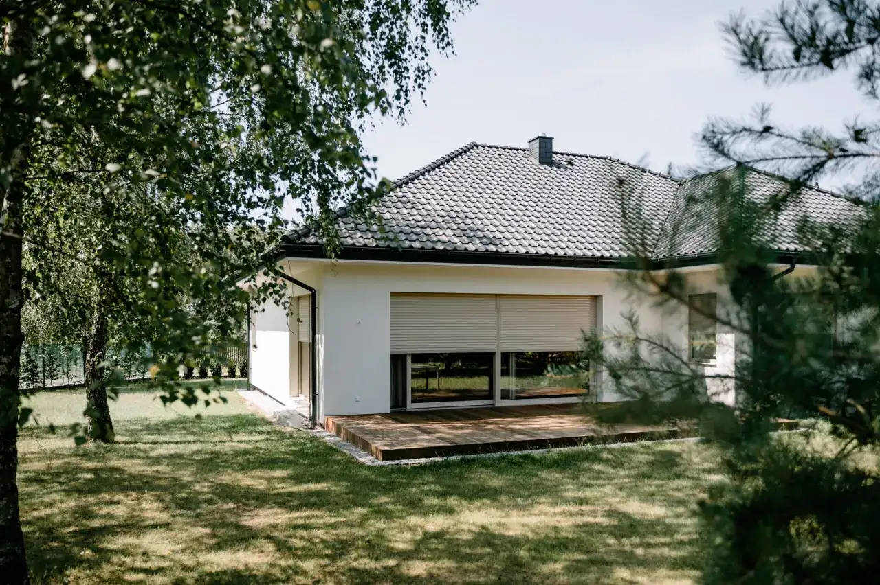 Nowoczesny dom z tarasem i roletami. Okna dąb bielony realizacje podkreślają elegancję.