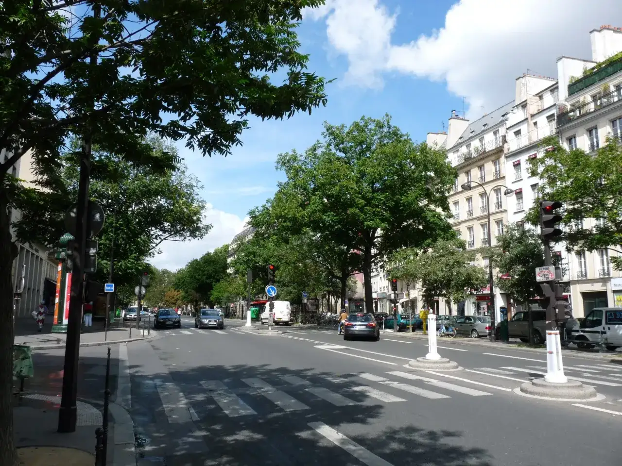Ulica w 11 dzielnicy Paryża, z drzewami, budynkami i ruchem ulicznym.