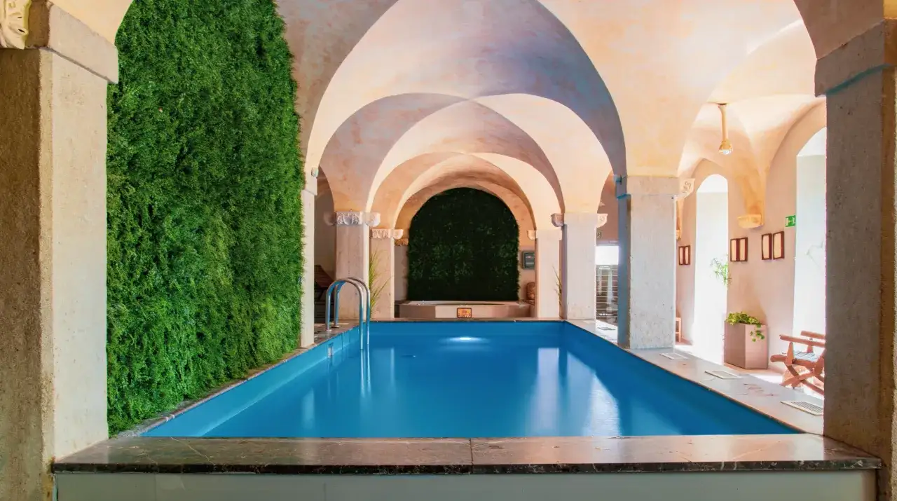 Relaks w hotelu spa na Dolnym Śląsku. Wnętrze z basenem, zieloną ścianą i łukowym sufitem.