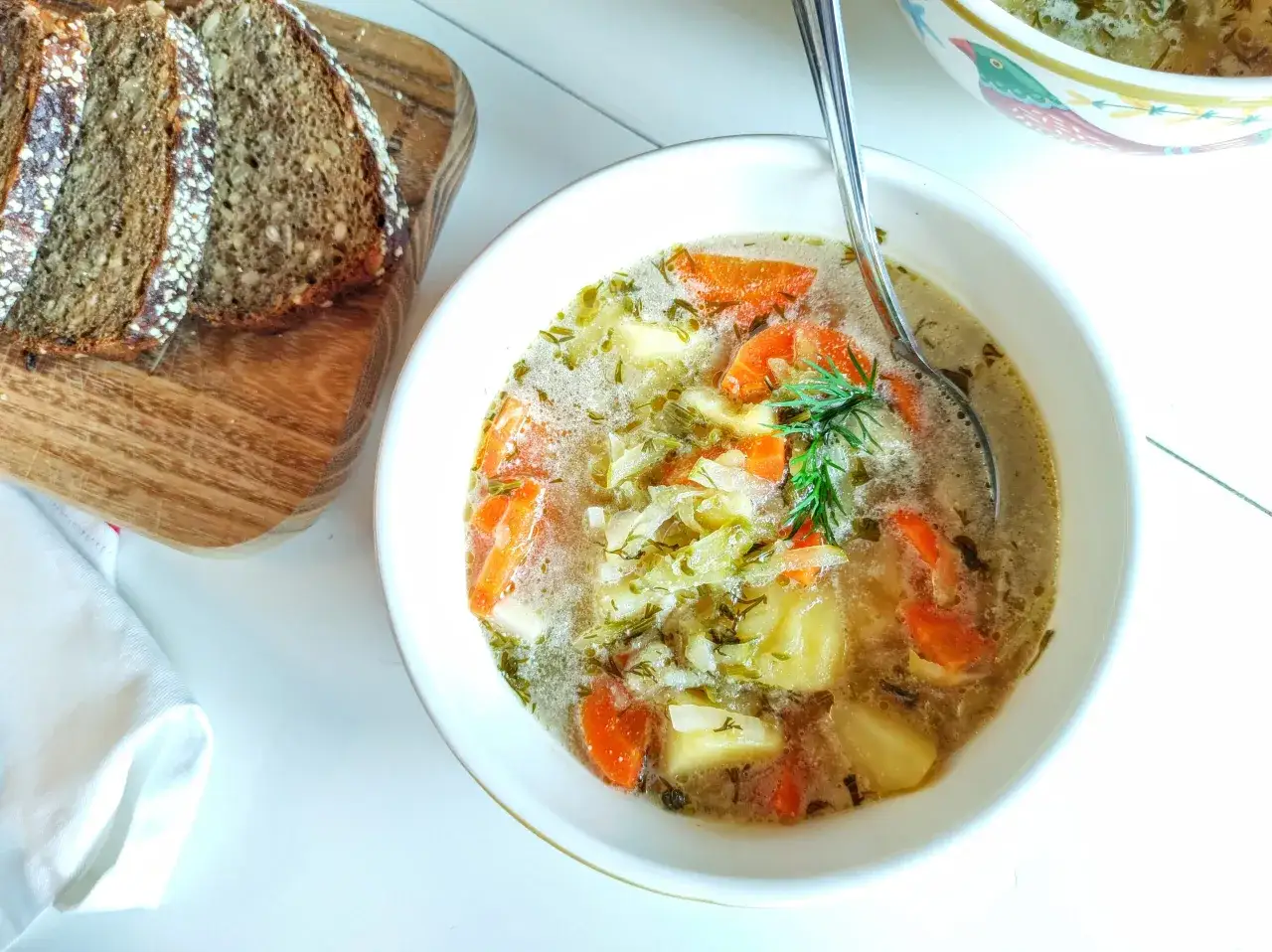 Pyszna zupa ogórkowa bez mięsa, pełna warzyw i z koperkiem, podana z kromkami ciemnego chleba.