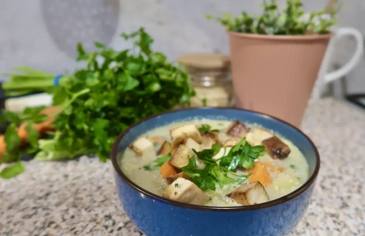 Aksamitna zupa ogórkowa bez mięsa, z kawałkami pieczonych ziemniaków i marchewki, udekorowana natką pietruszki.
