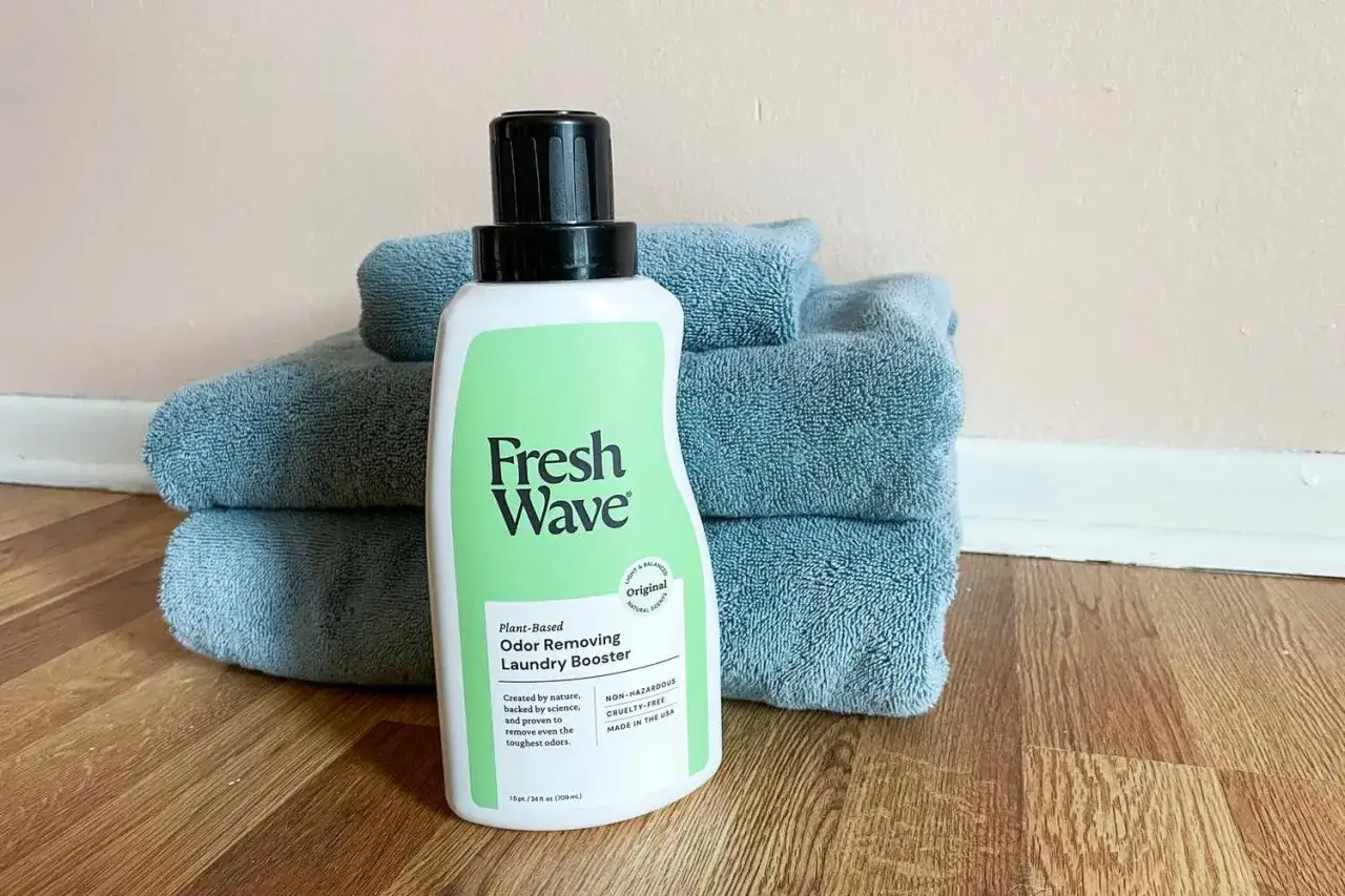 Butelka Fresh Wave Laundry Booster i stos ręcznik&oacute;w. Skuteczny spos&oacute;b, jak pozbyć się zapachu potu z ubrań.