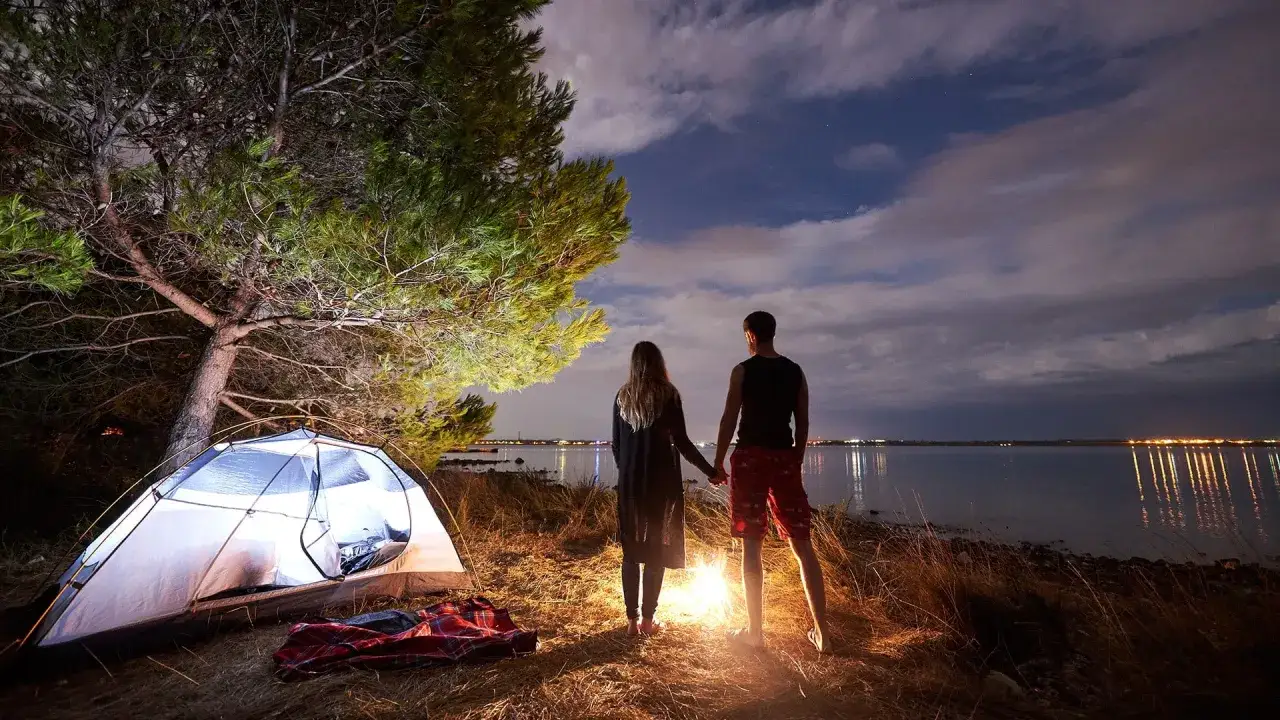 Para jak wzbudzić w nim tęsknotę, stoi przy ognisku nad jeziorem nocą, obok namiotu.