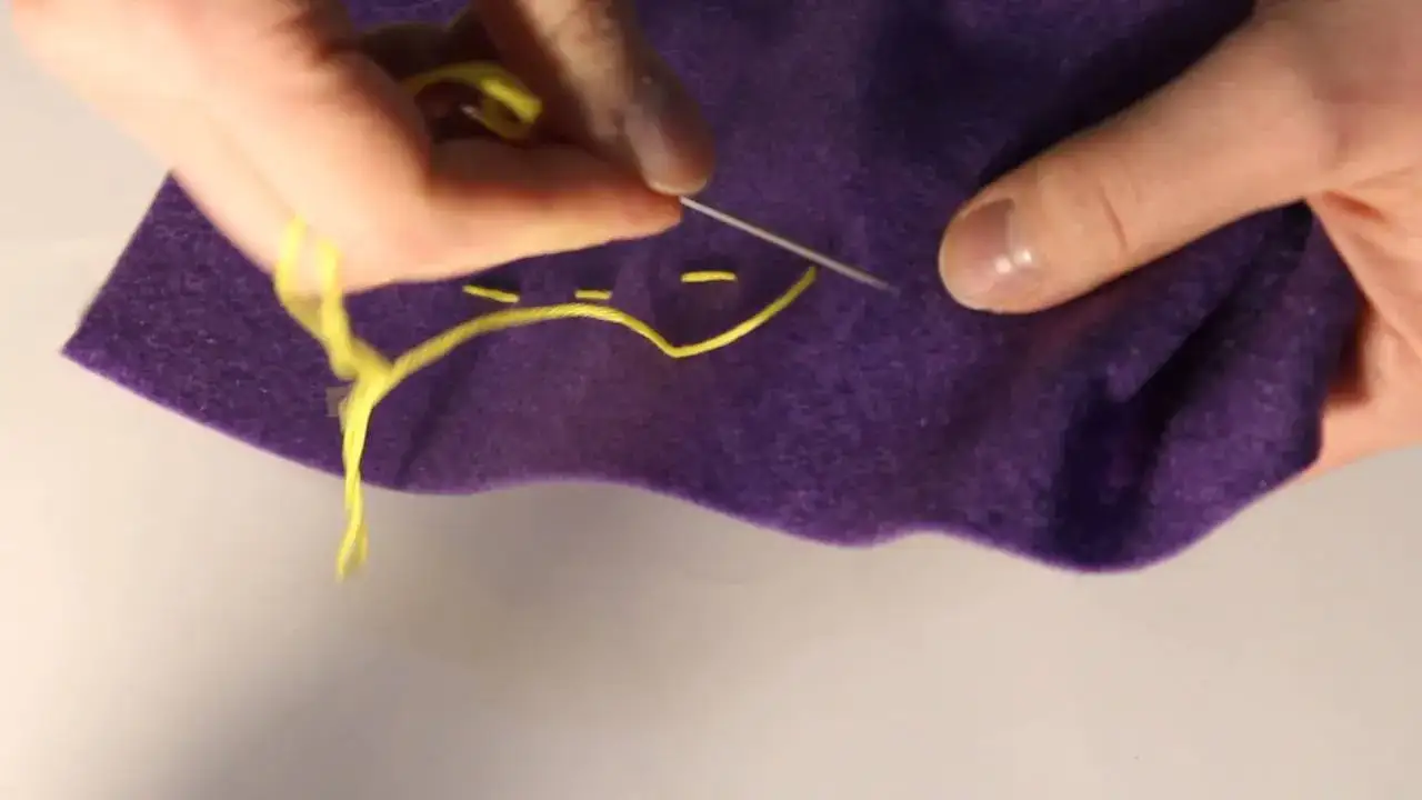 zbliżenie na dłonie szyjące ręcznie ściegiem za igłą