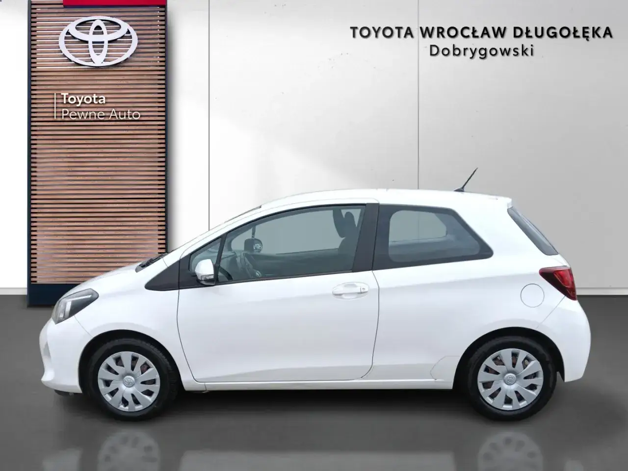 Biała Toyota Yaris na tle salonu. Dowiedz się, ile kosztuje Toyota Yaris w salonie Toyota Wrocław Długołęka Dobrygowski.