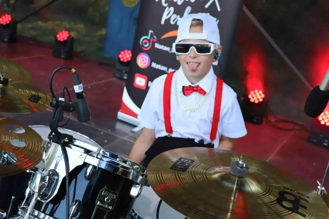 Młody perkusista, Zbigniew Kucharski, w okularach i z czerwoną muszką, gotowy do rock'n'rolla.