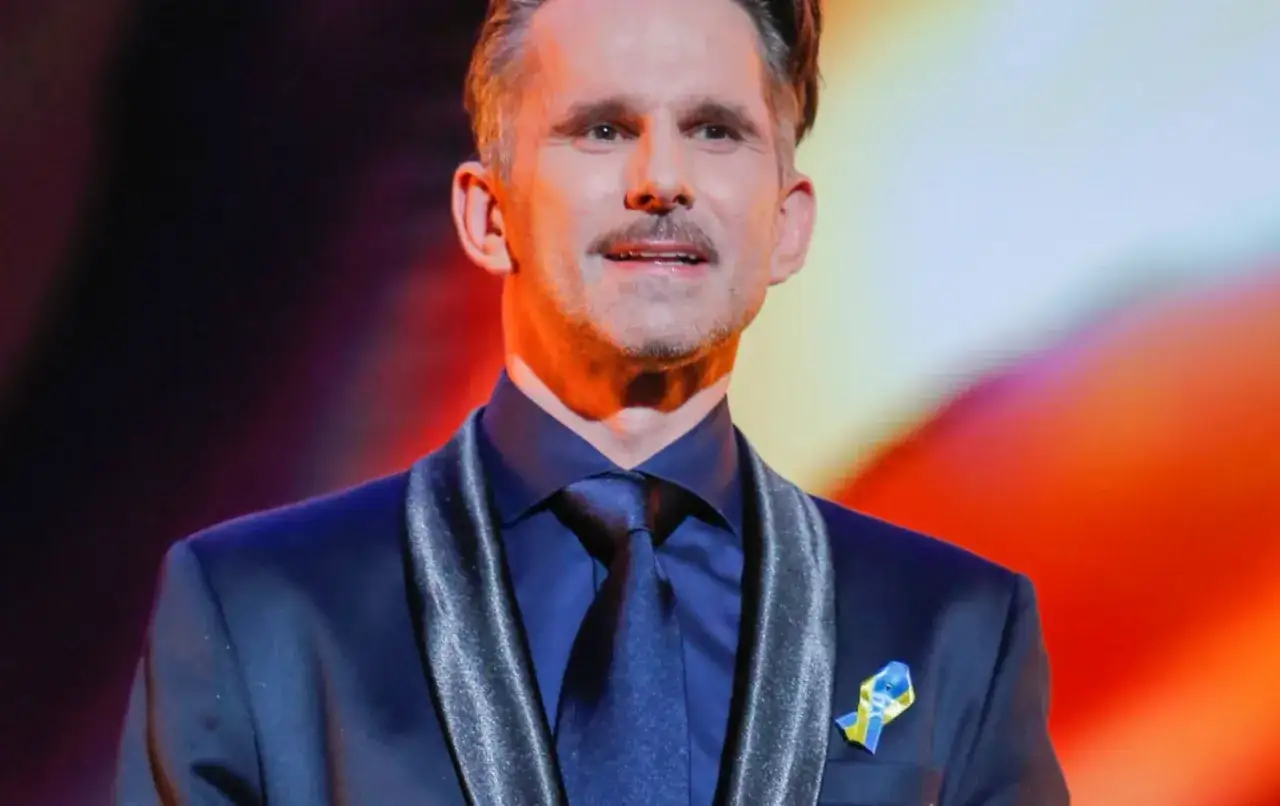 Mężczyzna w garniturze z przypinką w barwach Ukrainy. Czy to jego zarobki w filmie?