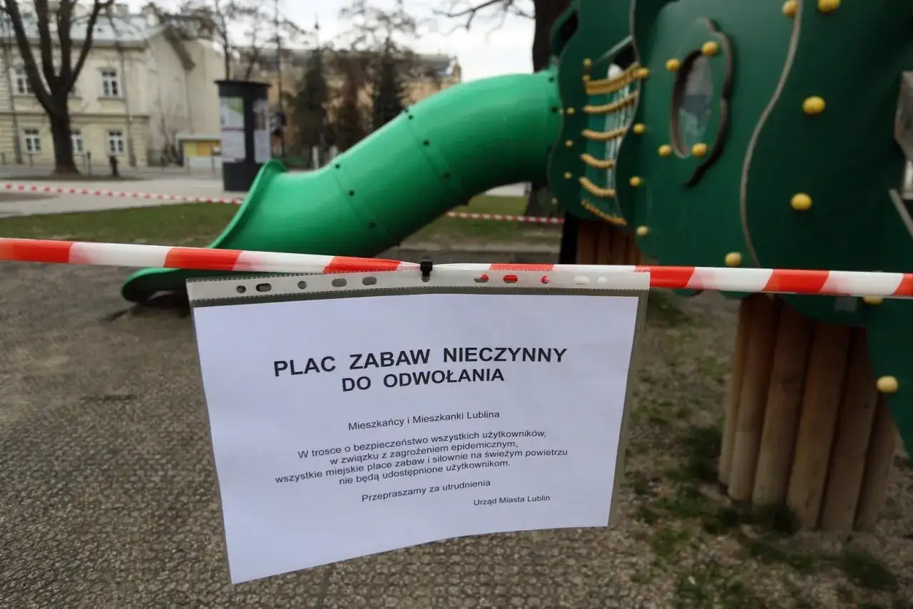 Zamknięte place zabaw do odwołania. Czerwono-biała taśma i tabliczka informują o tymczasowym zakazie korzystania z atrakcji dla dzieci.