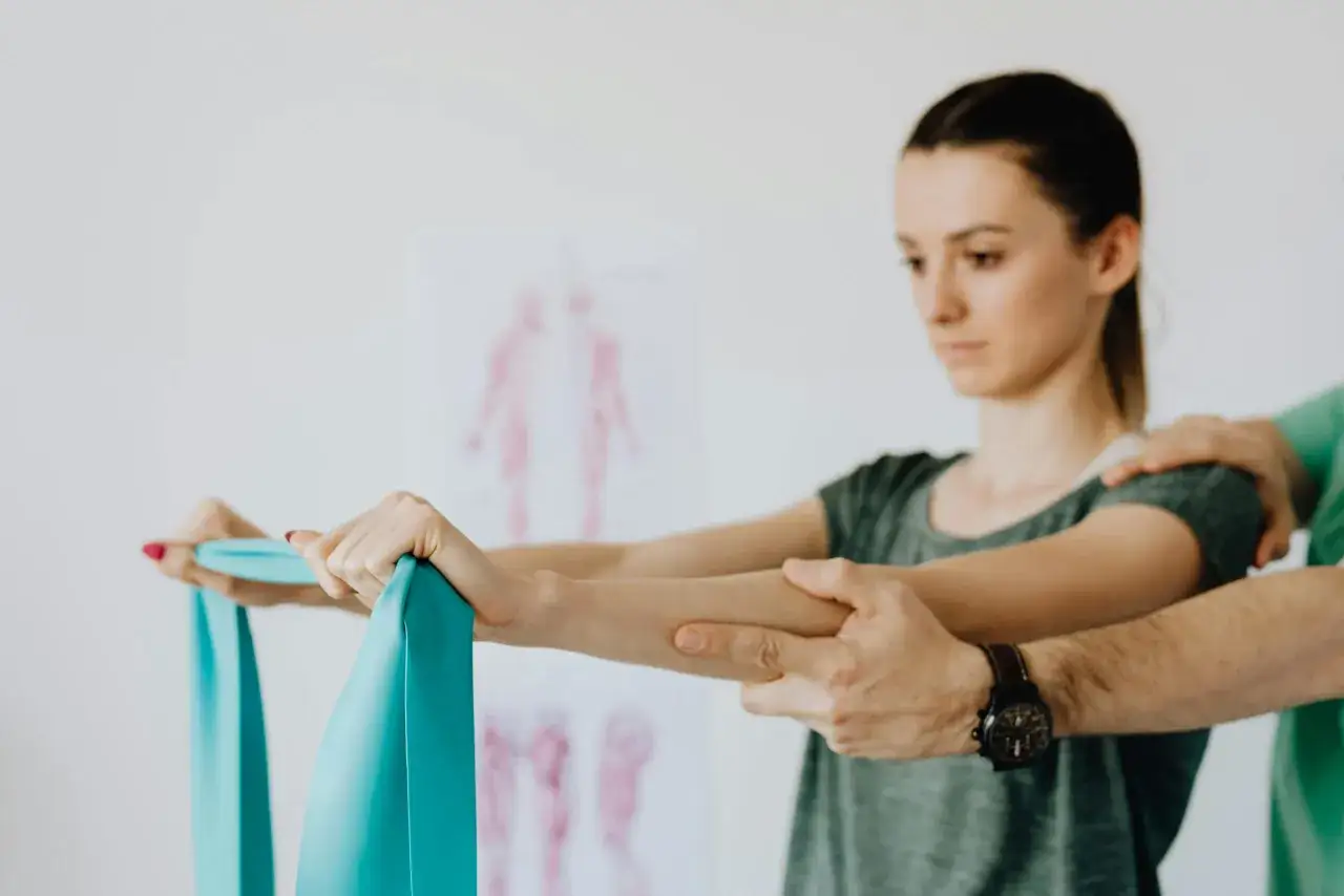 Fizjoterapeuta pomaga pacjentce z osteoporozą ćwiczyć z taśmą oporową.