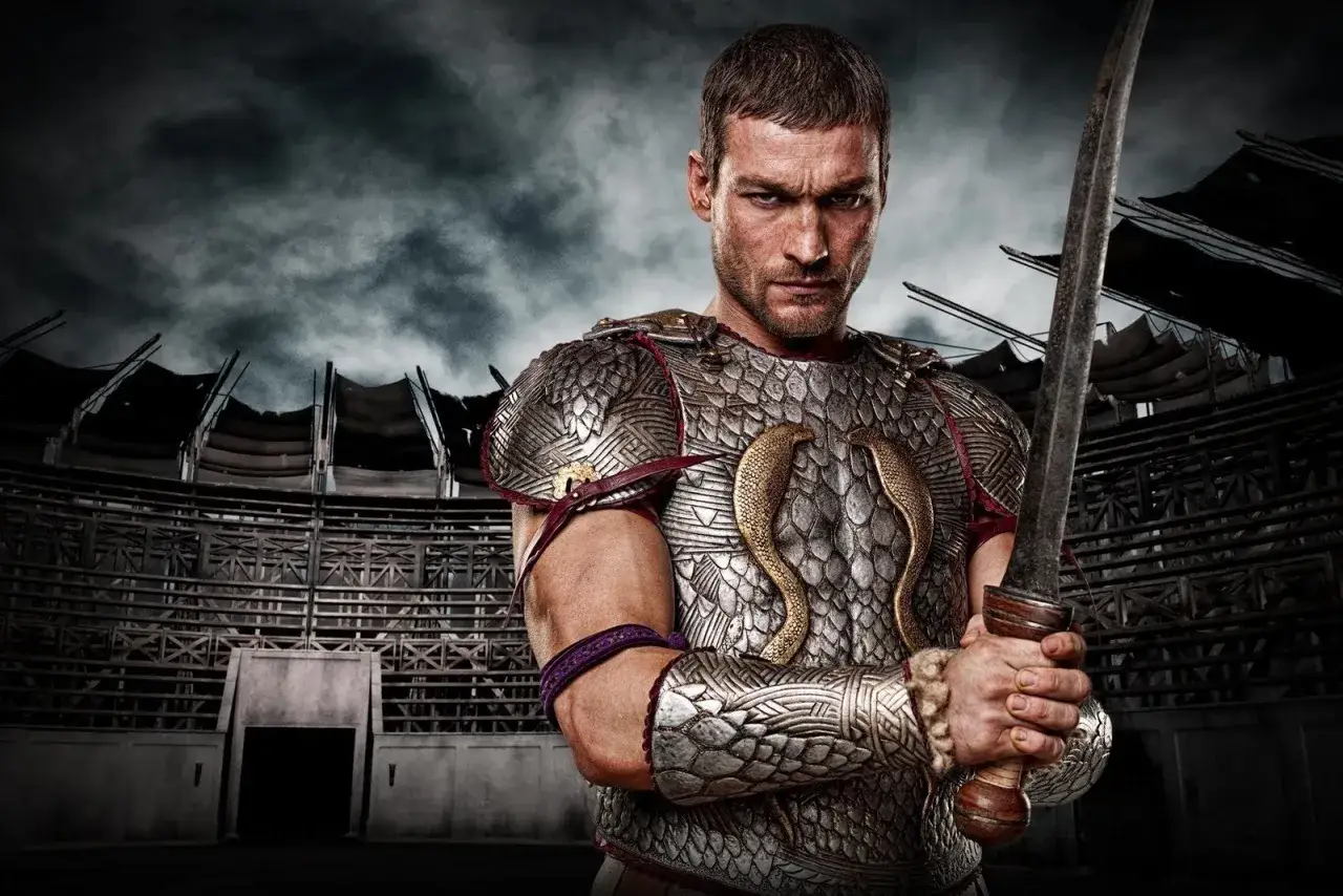 Spartakus serial gdzie obejrzec? Gladiator w zbroi z mieczem na tle amfiteatru.
