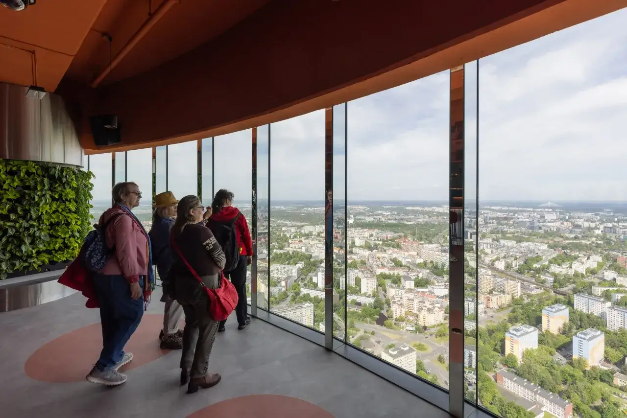 Grupa osób podziwia panoramę miasta z tarasu widokowego. Zastanawiasz się, ile pięter ma Skytower, patrząc na rozległy krajobraz z góry.