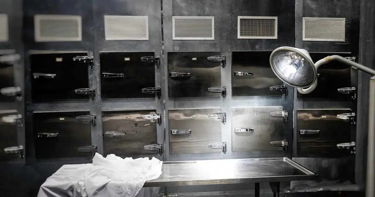 Chłodnia, czyli morgue po polsku, z rzędami metalowych drzwi i stołem sekcyjnym.