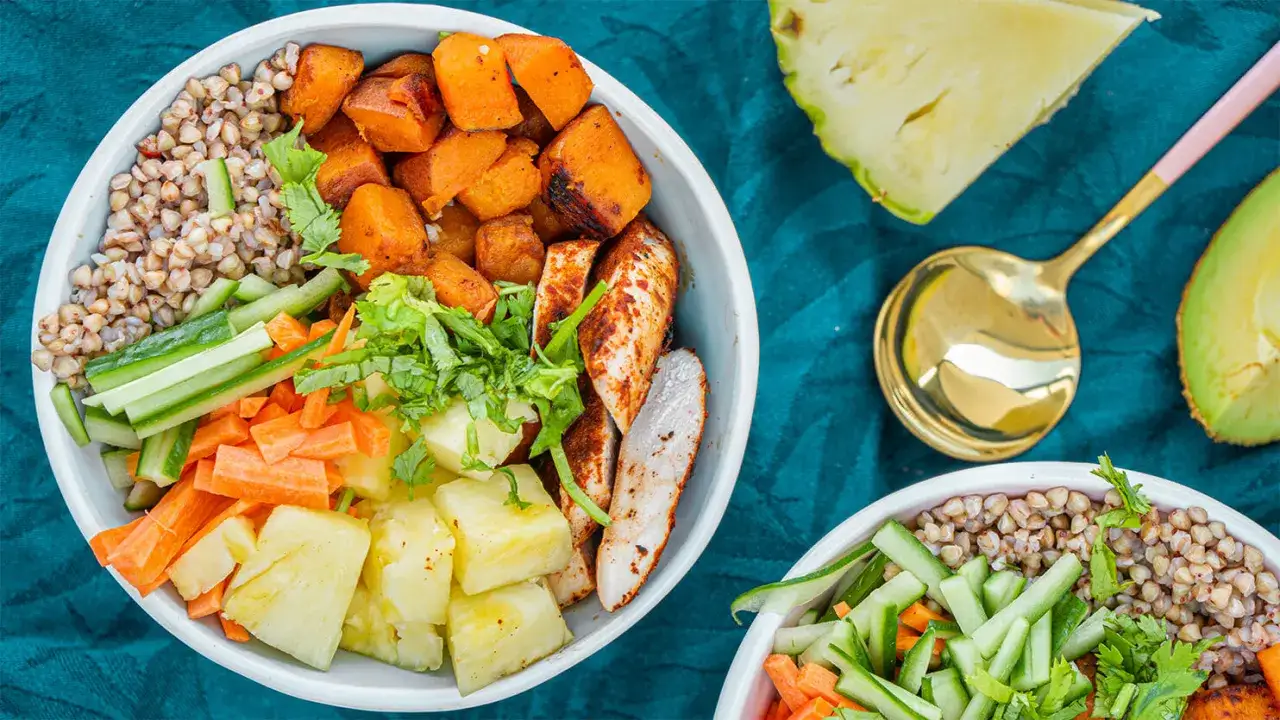 Zdrowy buddha bowl z kurczakiem, kaszą gryczaną, pieczonym batatem, ananasem, ogórkiem i marchewką.